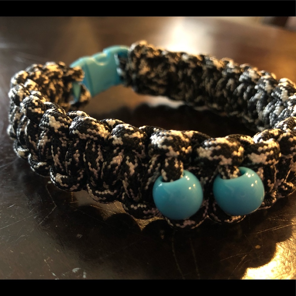 A black and white paracord bracelet w/ blue beads